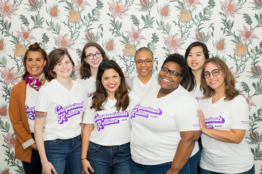 Staff members pose wearing Feminist Women’s Health Center t-shirts that read, “Compassionate Healthcare since 1976”