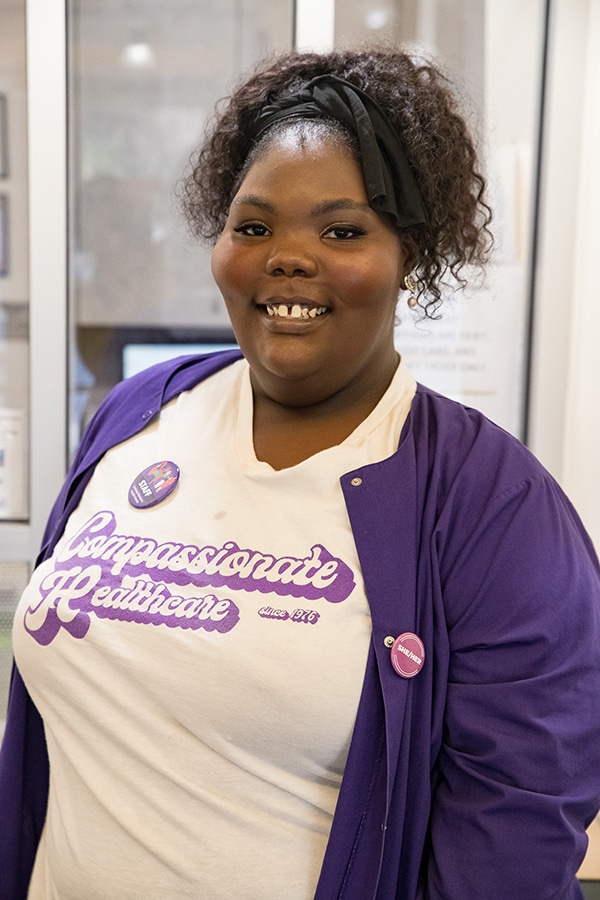 Clinic staff member smiles in a Feminist Women’s Health Center t-shirt.