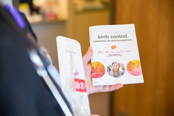 A close-up image of a clinic staffer holding a pamphlet on birth control options.