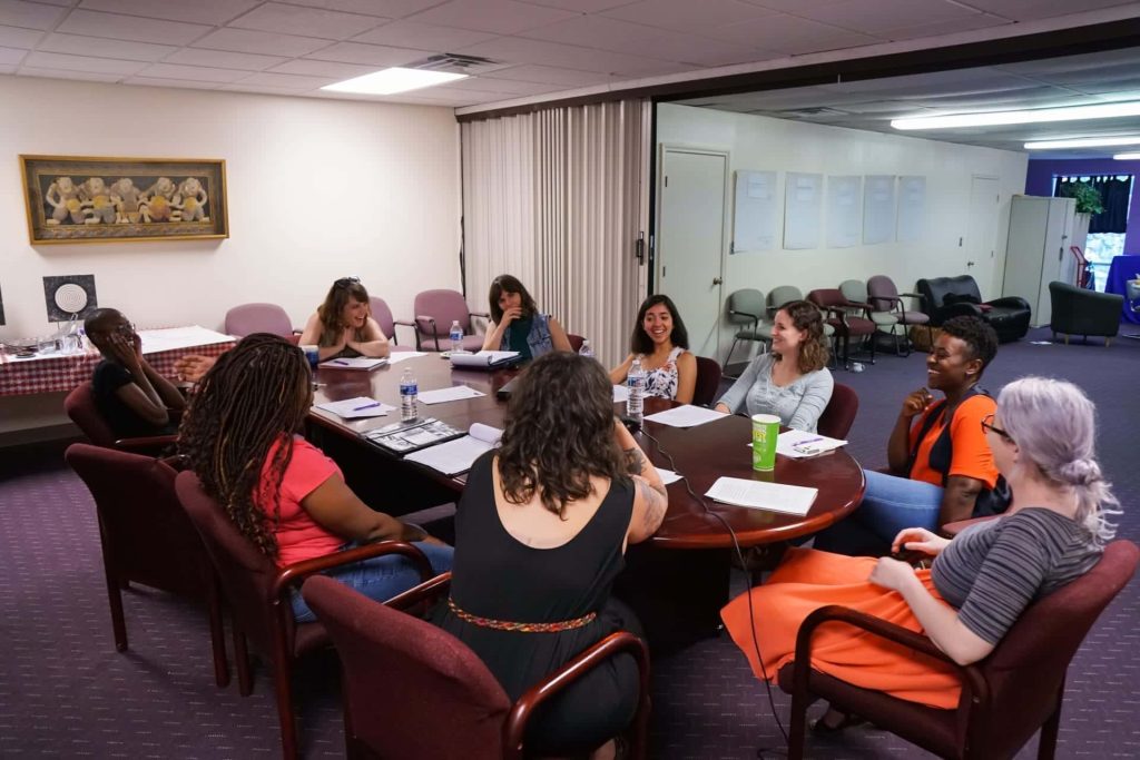 Clinic staff members and volunteers have a discussion at a conference table in the clinic.