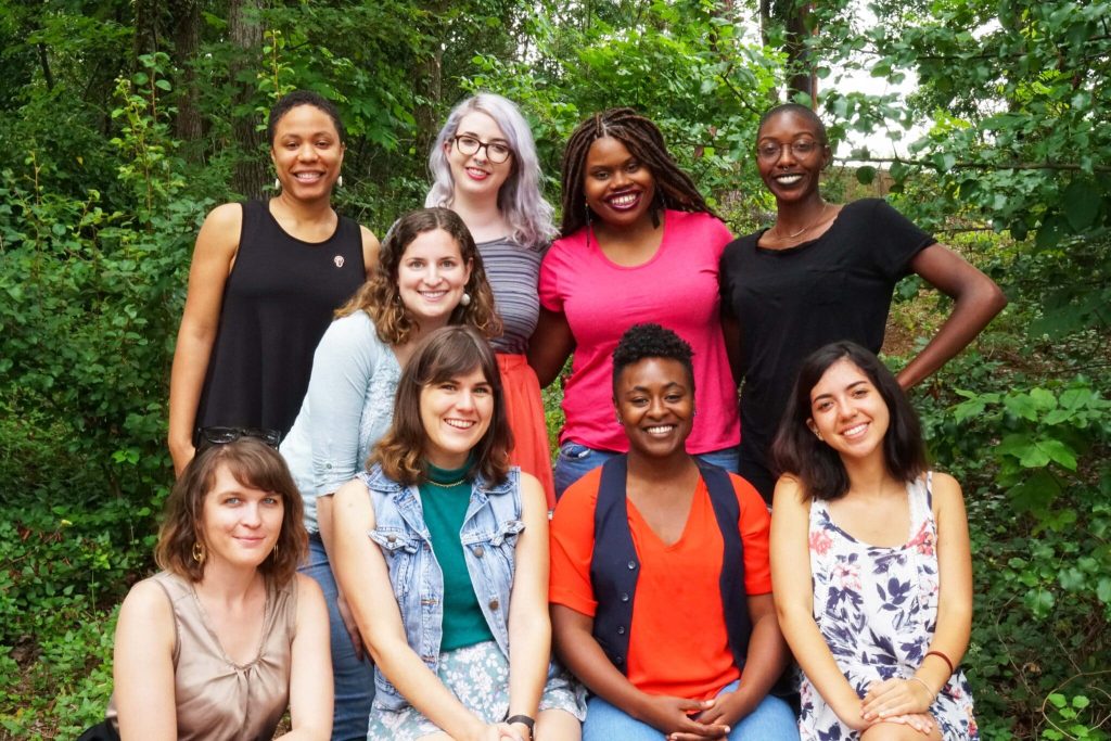 A group of interns poses for a photo outside.