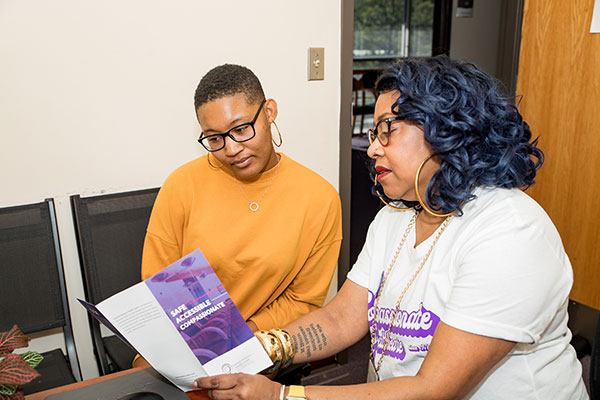 A clinic staffer presents a pamphlet to a model posing as a patient.
