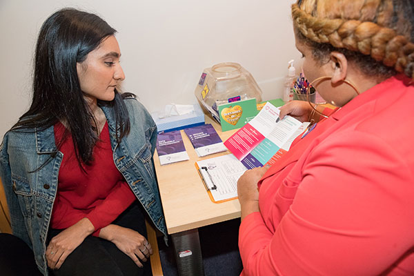 A clinic staffer presents a pamphlet to a model posing as a patient.