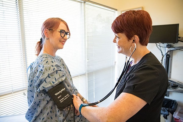 A model poses as a patient having their blood pressure taken by a clinic staffer.