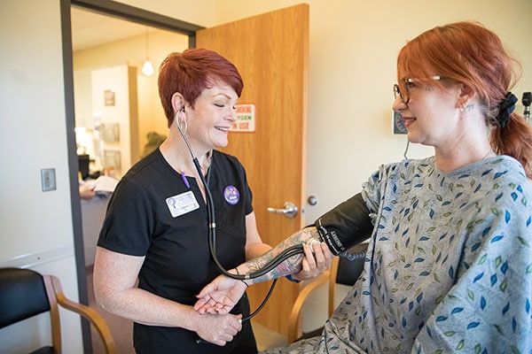 A model poses as a patient having their blood pressure taken by a clinic staffer.