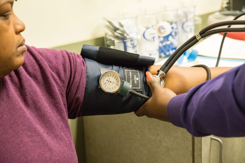 A model poses as a patient having their blood pressure taken by a clinic staffer.