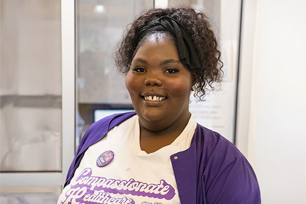 Clinic staff member smiles in a Feminist Women’s Health Center t-shirt.