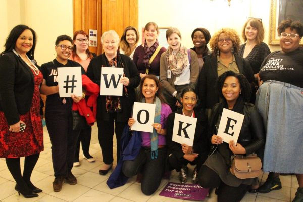 Group of the legislative advocacy program members pose together holding up signs that spell #woke.