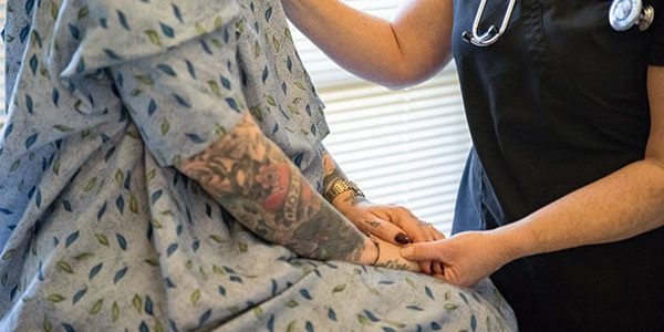 A close-up image of a staffer holding the hand of a model posing as a patient.