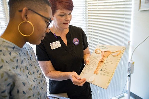 A clinic staffer shows a model posing as a patient an image of the female reproductive system.
