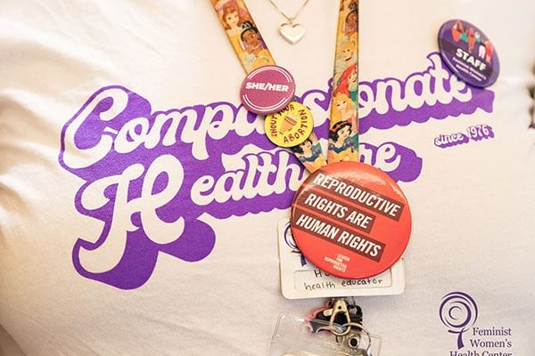 A close-up image of a staff member wearing a “Compassionate Healthcare since 1976” t-shirt.