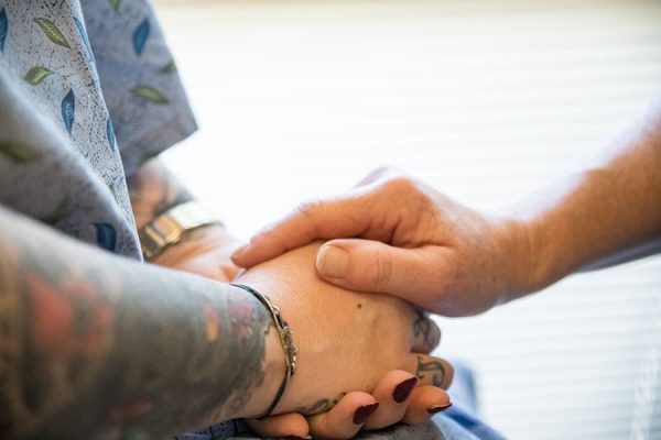 A close-up of a staff member holding the hand of a model posing as a patient.